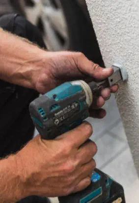closeup of handyman using drill on wall